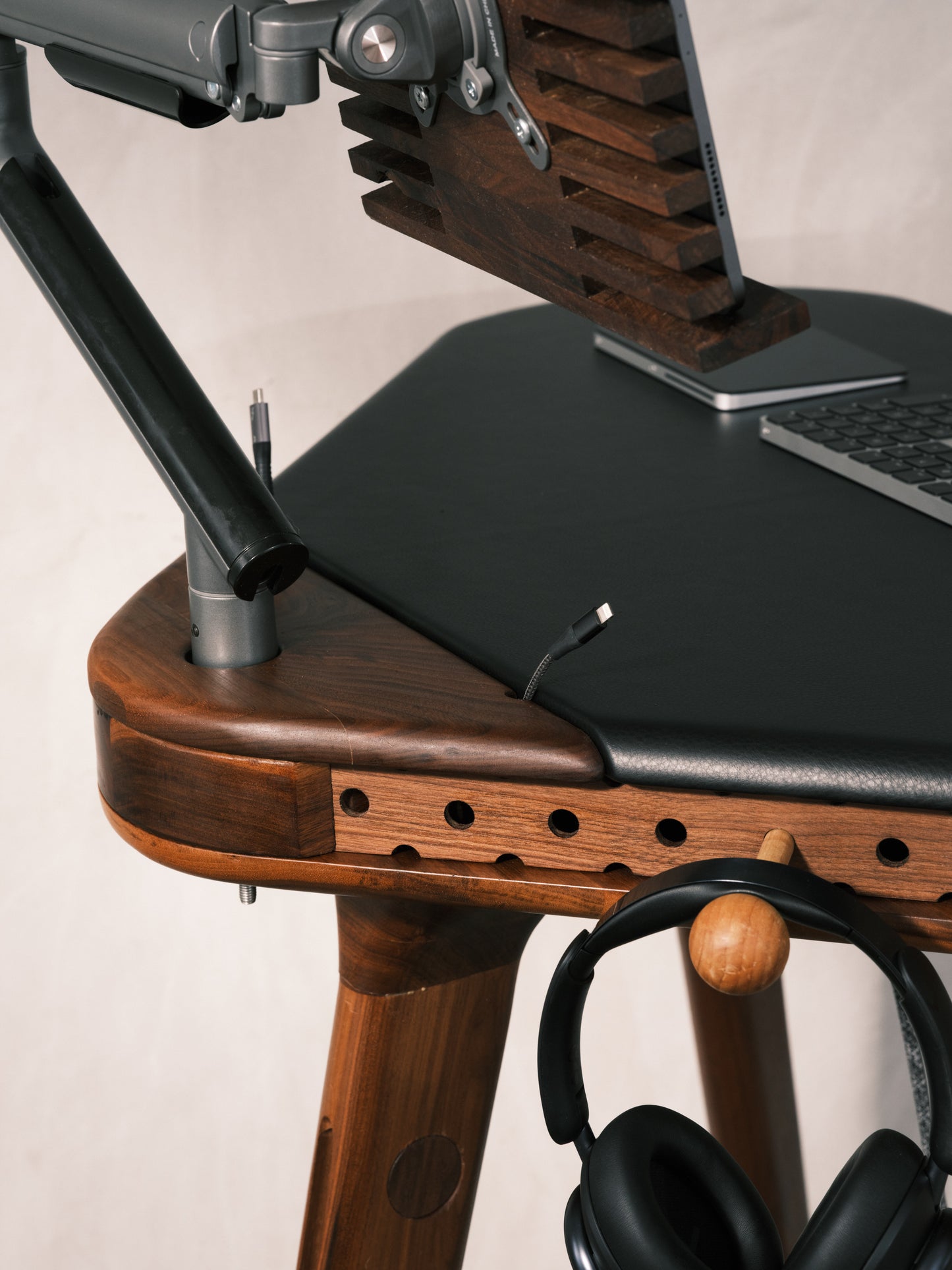Wooden standing desk with laptop stand and headphones on a neutral background